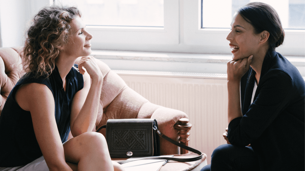 A female client seats across from her female mindset coach during a coaching session | "What is a Mindset Coach? 3 Important Steps to Becoming a Mindset Coach" | GrowPredictably